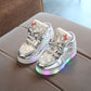 Kids flashing sneakers, metallic silver stars and red bow, angled front with multicolor LED sole