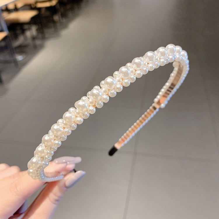 Pearl beaded headband held at an angle, curved band with black comb insert