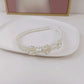 White pearl headband with three rows and two small rose appliques across the front