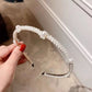 White pearl headband with tight bead row and black grip ends, held for display