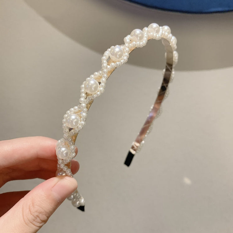White pearl headband with evenly spaced pearls and black grip ends along the arc