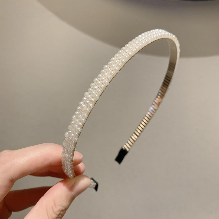 White pearl headband with dense beading and black grip ends, viewed from the side