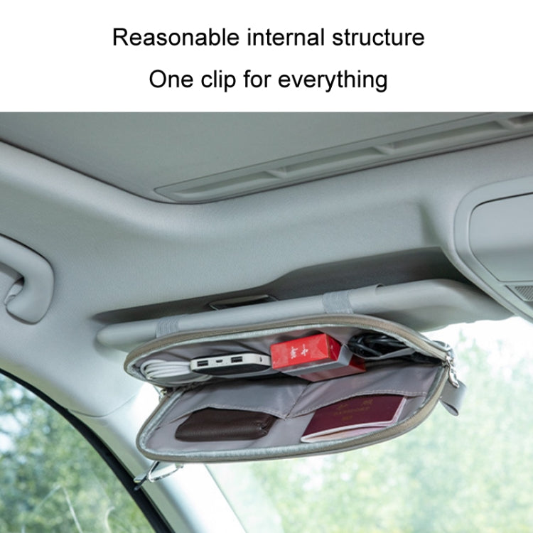 Car sun visor storage bag hanging inside the vehicle with compartments for cards and glasses
