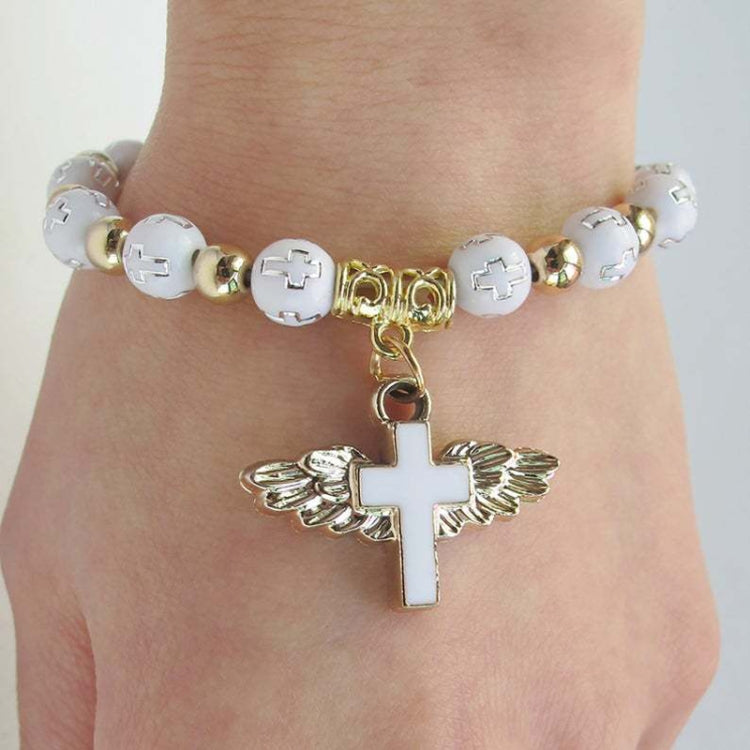 Angel cross bead bracelet on wrist with white beads, gold spacers, and cross charm.