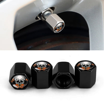 Black metal tire valve cap set with skull emblem, shown installed on a car wheel valve.