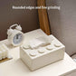 White building-block tissue storage box on tabletop with tissue peeking from slot