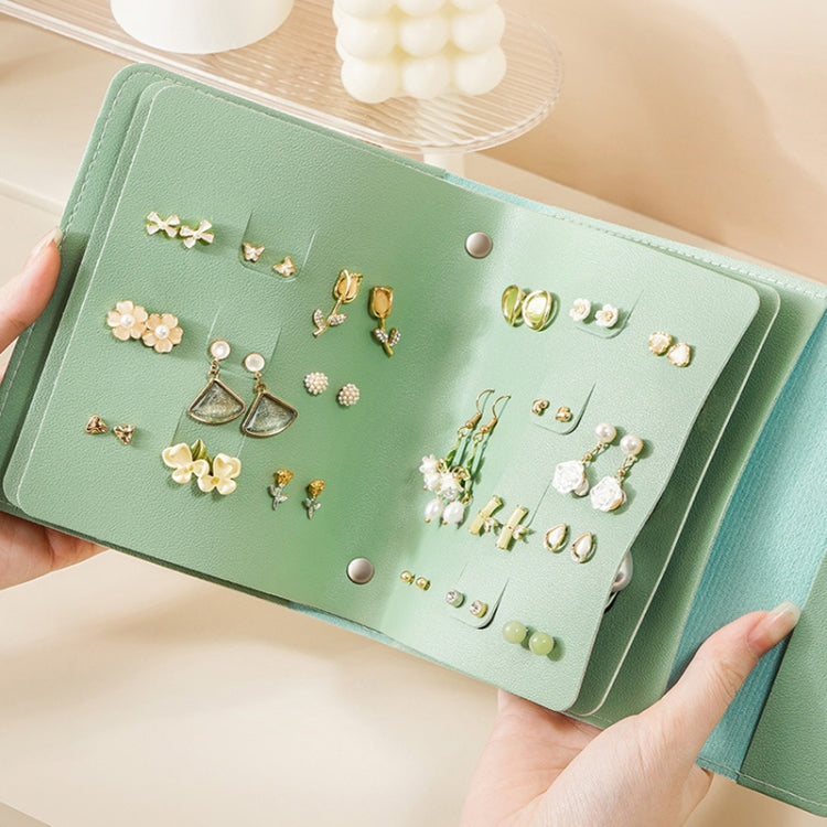 Book-shaped jewelry bag, green, open with multiple earrings in front compartments