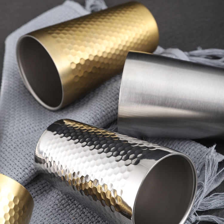 Hammer-finish stainless steel mugs in gold and silver, angled on cloth
