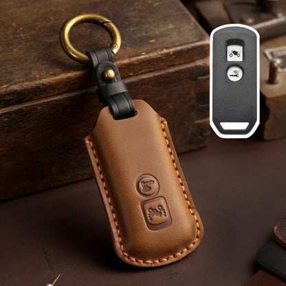 Brown leather motorcycle key case with gold ring and embossed buttons, stitched edge.
