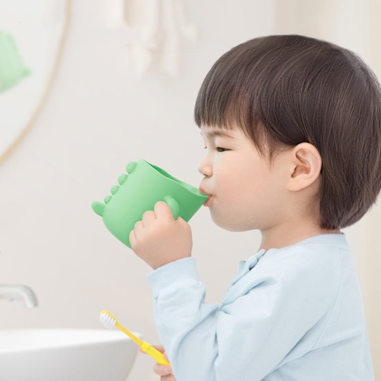 Dinosaur cartoon brushing cup with green finish, used by a child