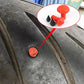 Red tire repair plug inserted in tire tread cut, with black cone pieces
