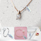 Rose-gold necklace and ring with jewelry price tags on light gray stone