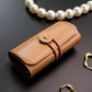 PU leather-style jewelry roll with snap closure and wrap strap, tan-brown