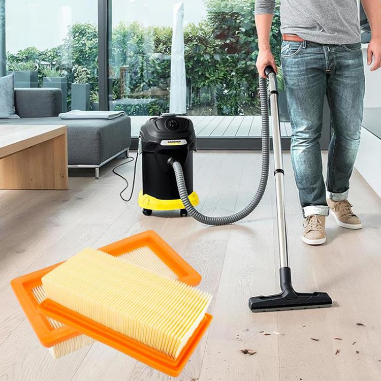 Orange vacuum cartridge filter with pleated paper media on floor beside canister vacuum