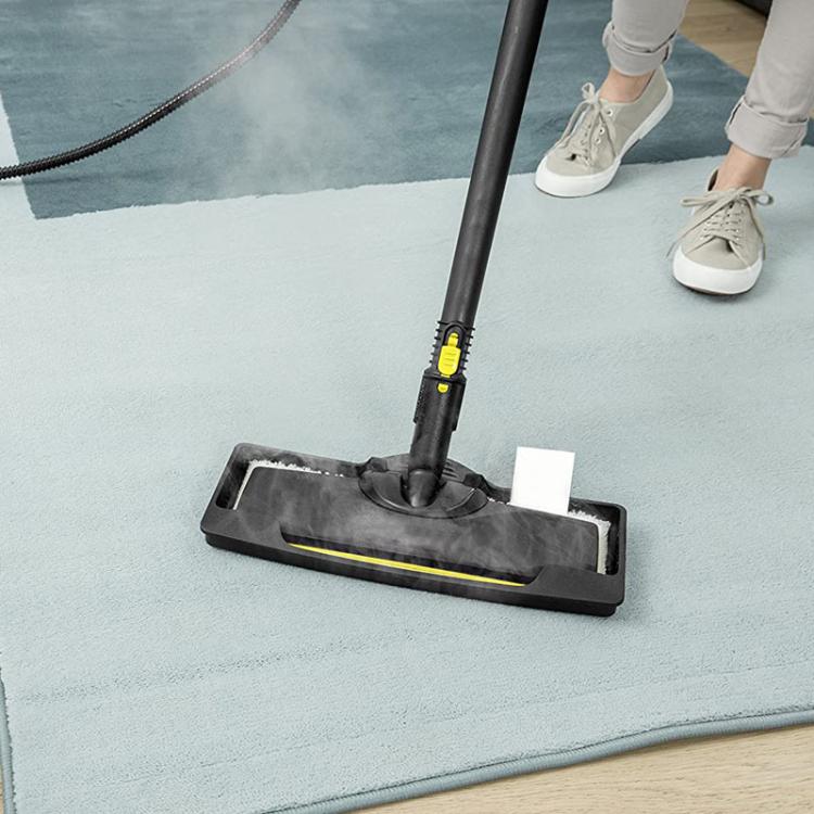 Carpet glider attachment with steam nozzle cleaning a light rug on floor