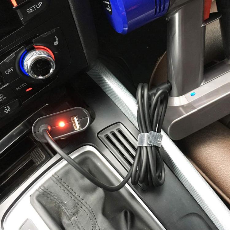 Car dashboard power socket with plugged-in Dyson vacuum charger and cable