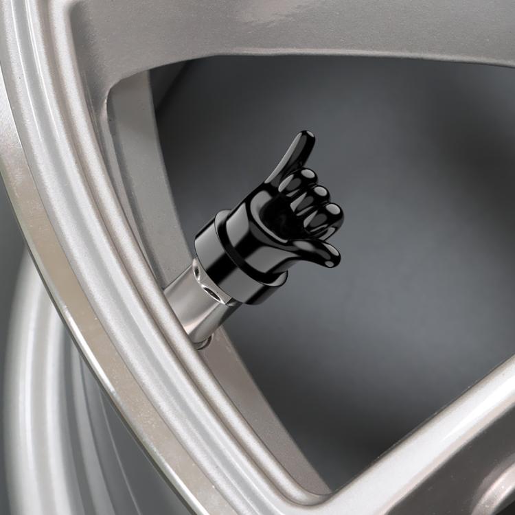 Black hand-gesture tire valve cap installed on car wheel rim