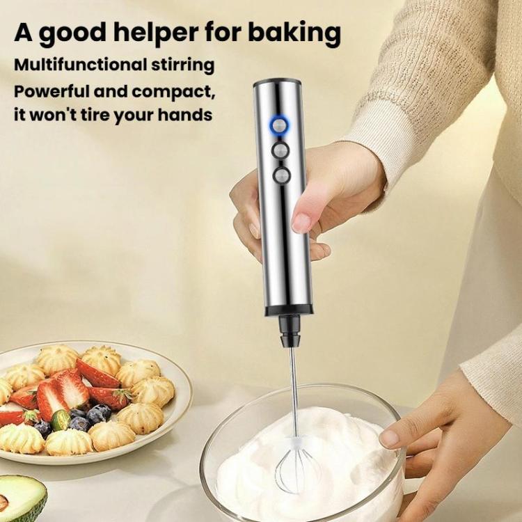 Handheld electric milk frother held in hand, mixing whisk head over froth