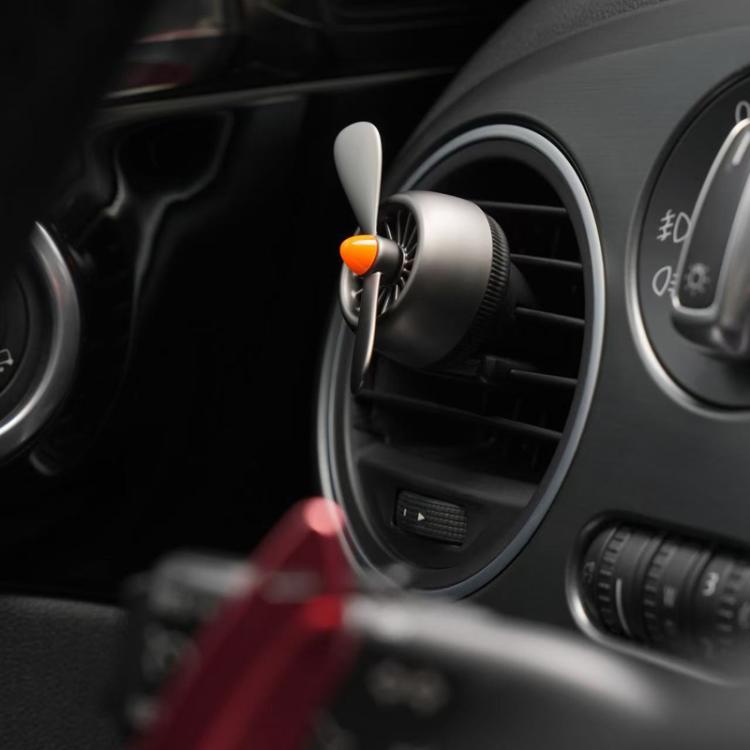 Car air vent air freshener ornament with orange-topped cap clipped in vent
