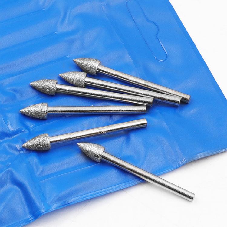 Pointed diamond grinding heads, silver rods with textured cone tips on a blue holder sheet