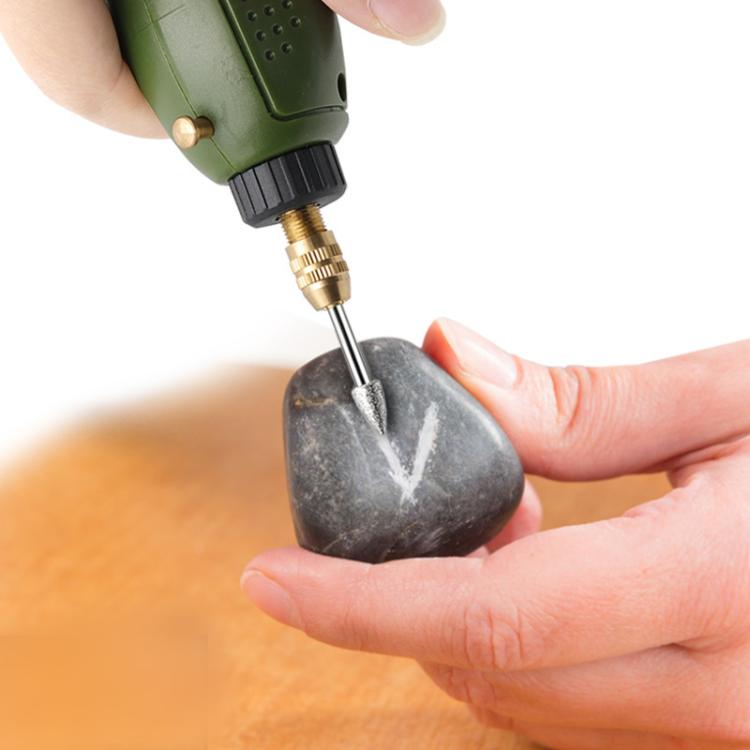 Pointed diamond grinding head in a rotary tool, engraving a dark stone surface