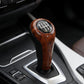 Dark brown wood-grain 6-speed gear shift knob installed in car console with black trim