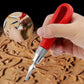 Red-handled engraving knife held above carved wooden design with silver blade tip