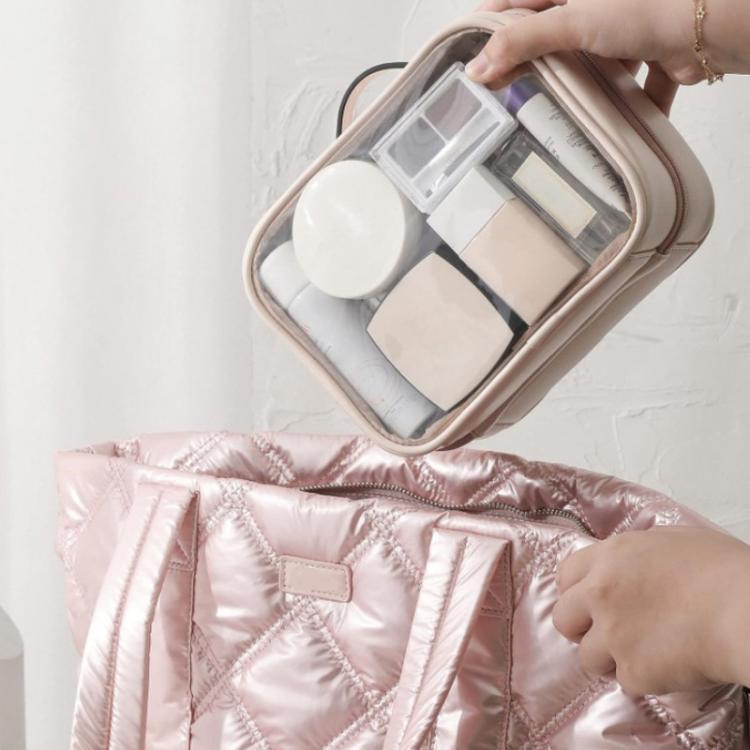 Pink quilted waterproof makeup bag held open with clear compartments and stored cosmetics
