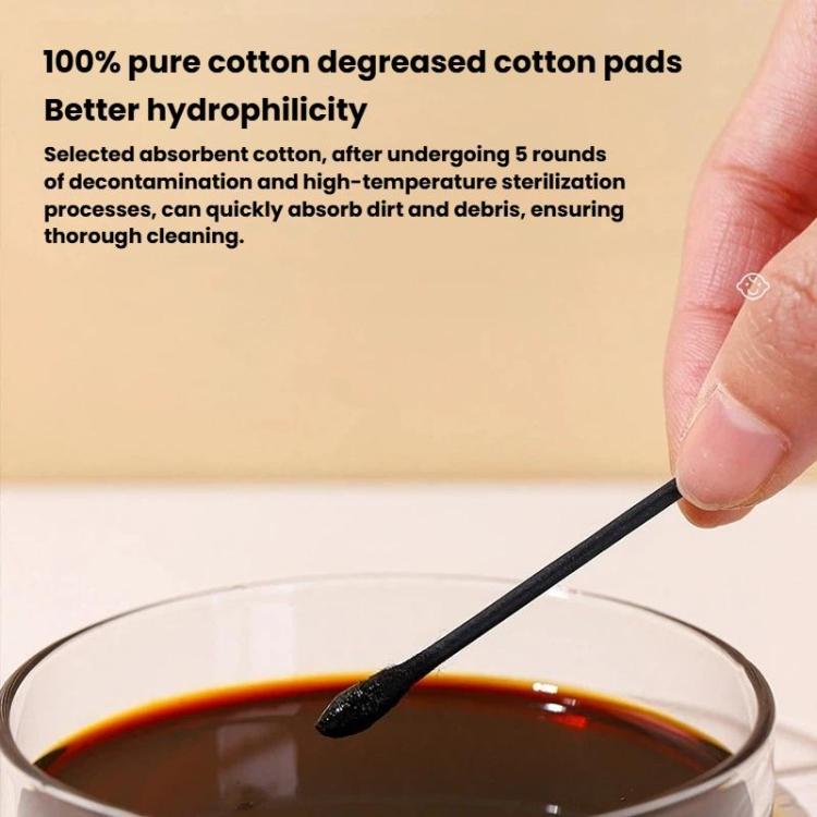 Hand holding a black cotton swab tip above a small cup of liquid
