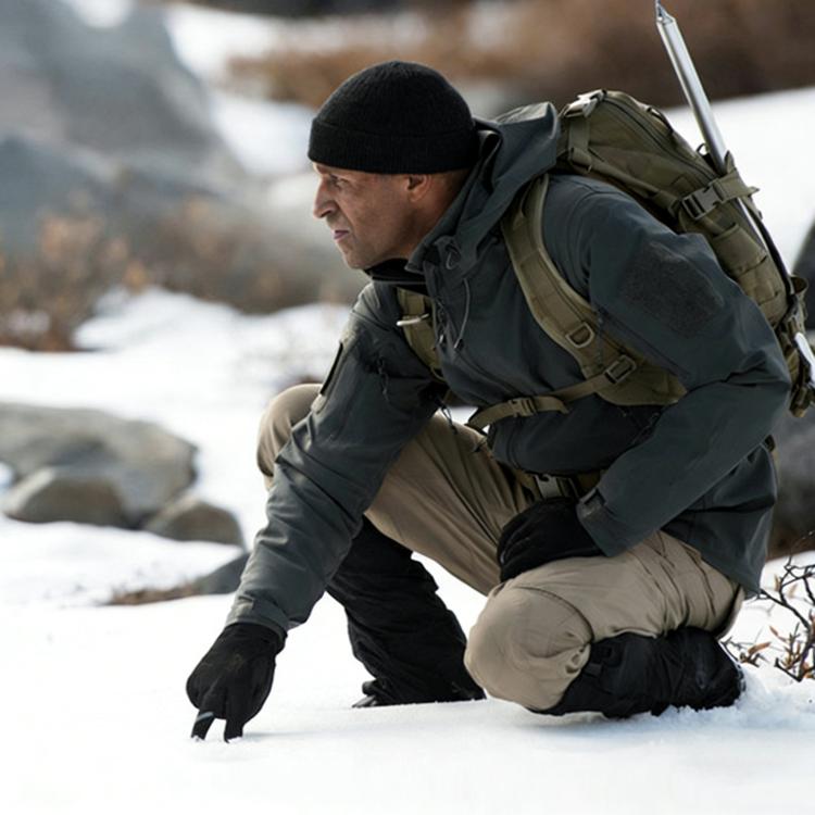 Fleece-lined waterproof pants worn by hiker kneeling outdoors in cold weather