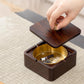 Wood magnetic ashtray with open square base, brass bowl, and hand lifting lid