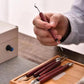 Clay sculpting knife with rosewood handle held above pottery, stainless steel blade