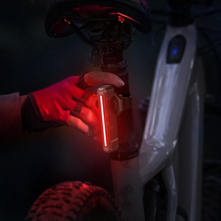 Bike taillight glowing red with a vertical light bar near the bicycle frame