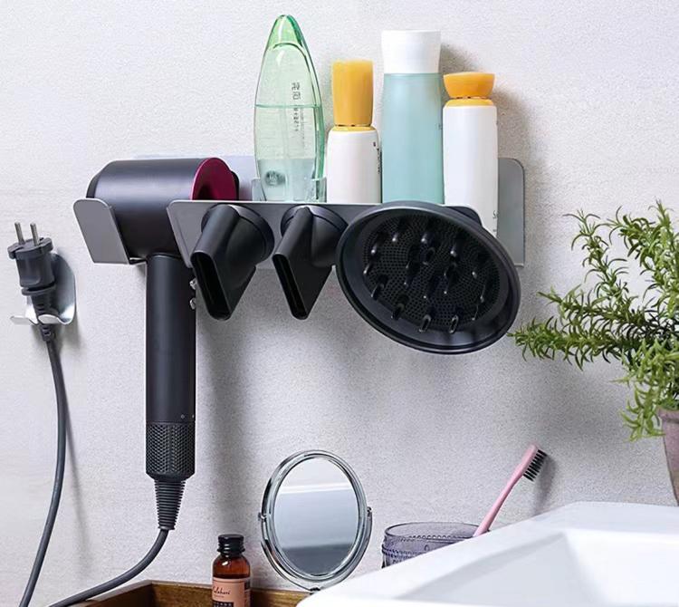 Wall-mounted hair dryer holder with diffuser head and nozzle attachments resting in slots.