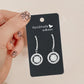 Black earring display card label with top hole and two hanging hoop earrings