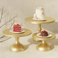 Gold tiered cake stand set holding cake and dessert slices on round plates