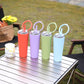 Assorted-color vacuum insulated sports cups with carry handles and straw lids on table
