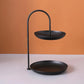 Black two-tier wrought iron serving tray with arched handle and shallow plates