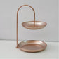 Rose gold two-tier wrought iron serving tray with arched handle and shallow plates