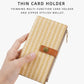 Beige straw-weave long wallet held in hand, side zipper with brown snap tab