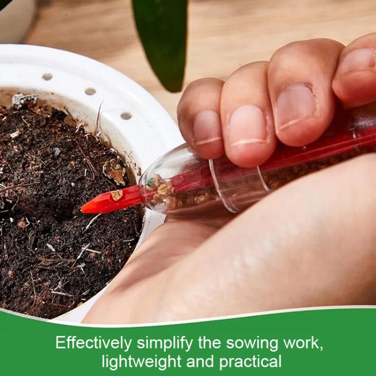 Red-tipped syringe seed planter in use, dispensing into soil near a hand