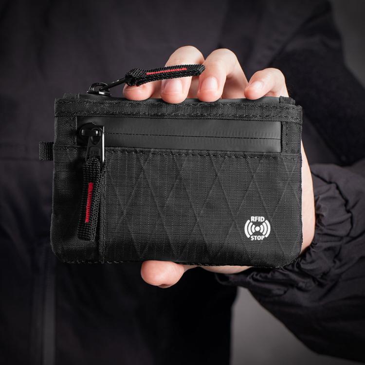 Black RFID card holder wallet held in hand with red-accent zipper