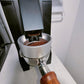 Silver magnetic dosing ring cup on grinder, holding a small amount of coffee grounds.