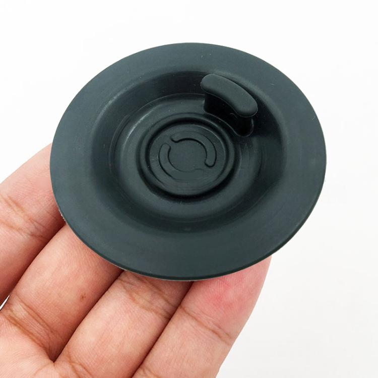 Blind filter backflush disk, dark gray rubber, held in hand with central valve detail