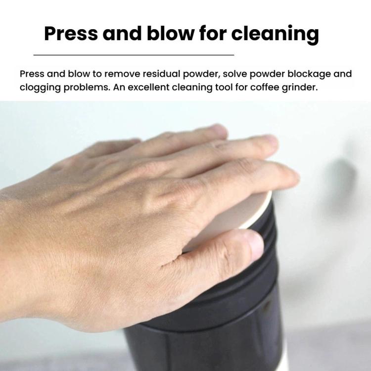 Hand pressing a black ribbed blowing hopper to clean a coffee grinder