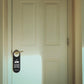 Black leather door hanger sign on a knob, “Please Do Not Disturb” side with Thank You text.