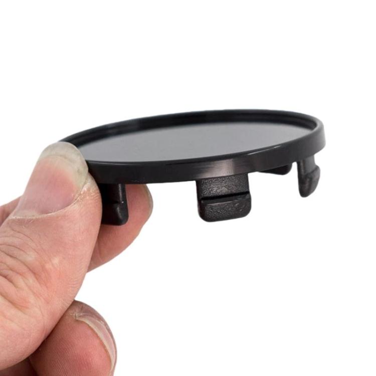 Black wheel hub center cap held in hand, clip tabs visible for installation.