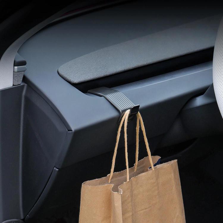 Dashboard hook holding two brown paper shopping bags from the car console