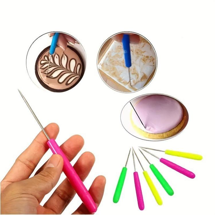 Clay sculpting tool set with pink and green detail needles, hand holding one tool