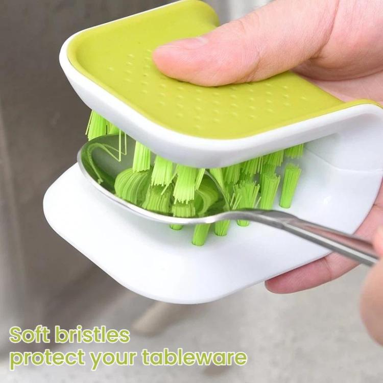 Hand using a green-bristle knife scrub brush on tableware